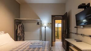 Une chambre d’hôtel équipée d’un lit, d’un bureau, d’une télévision et d’une porte donnant sur un balcon.