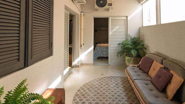 Un couloir étroit avec un canapé, un tapis à motifs et une plante en pot.