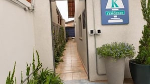 Un étroit sentier mène à l’entrée d’un bâtiment, où un panneau indique l’emplacement de la réception.