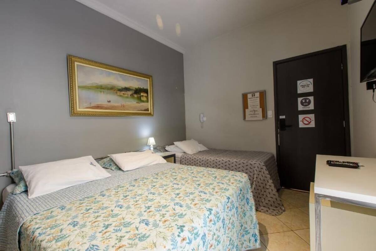 A room with two beds, a painting on the wall, a desk, and a door with signs.