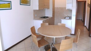 Una cocina compacta con una mesa redonda y sillas, una estufa pequeña y armarios.