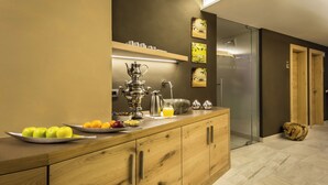 Una cucina moderna con un piano di lavoro in legno, una macchina da caffè, frutta e una porta vetrata che dà su un bagno.
