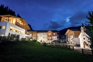 Un hotel moderno con diversi edifici, una zona verdeggiante e una piccola chiesa.