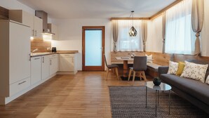 Una cucina moderna con mobili in legno, un'area pranzo con tavolo e sedie, un divano e una finestra con tende.