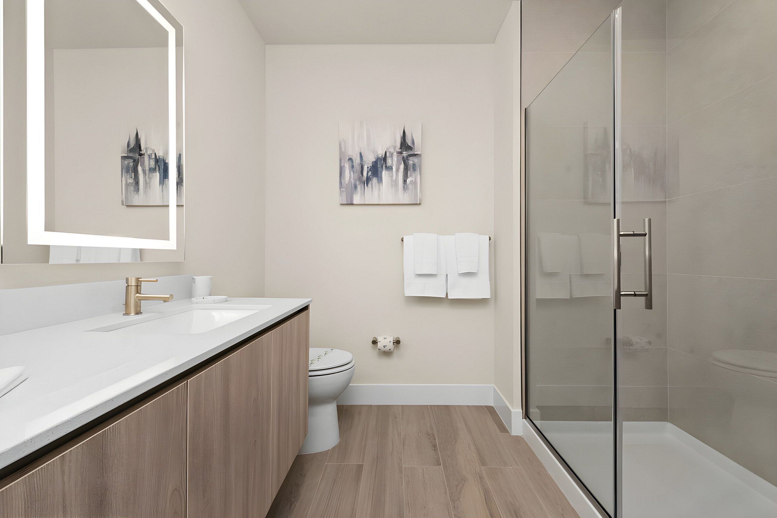 A modern bathroom with a glass shower enclosure, a double sink vanity, and two wall-mounted toilets.