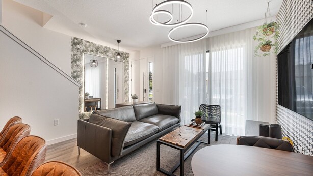 Uma sala de estar moderna com sofá, mesa de centro e área de jantar.