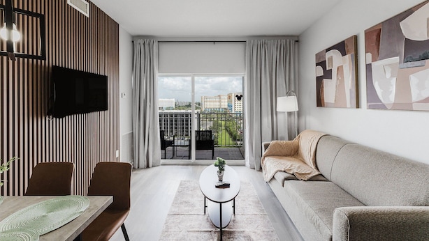 A modern living room with a sofa, a coffee table, and a TV mounted on the wall. - Resort Suite on International Drive (Orlando)