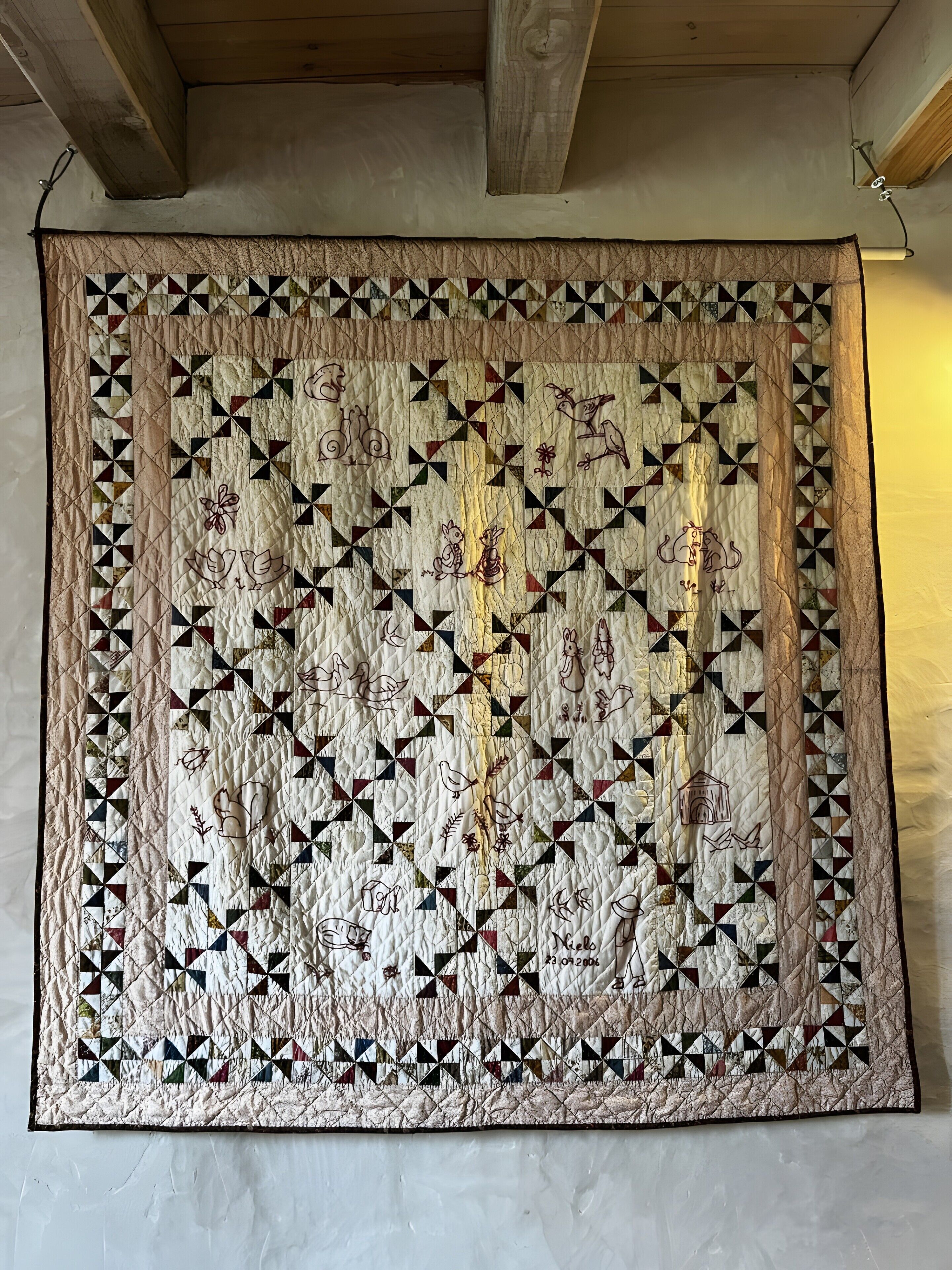 A large, detailed quilt hanging on a wall.
