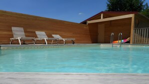 Ein Schwimmbecken mit Liegestühlen und einer Holzterrasse.