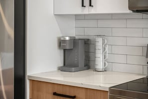 Eine Küche mit Kaffeemaschine, Tassenhalter und Schrank.