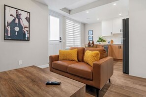 Ein modernes Wohnzimmer mit einem braunen Ledersofa, einem Holztisch und einer Fernbedienung.