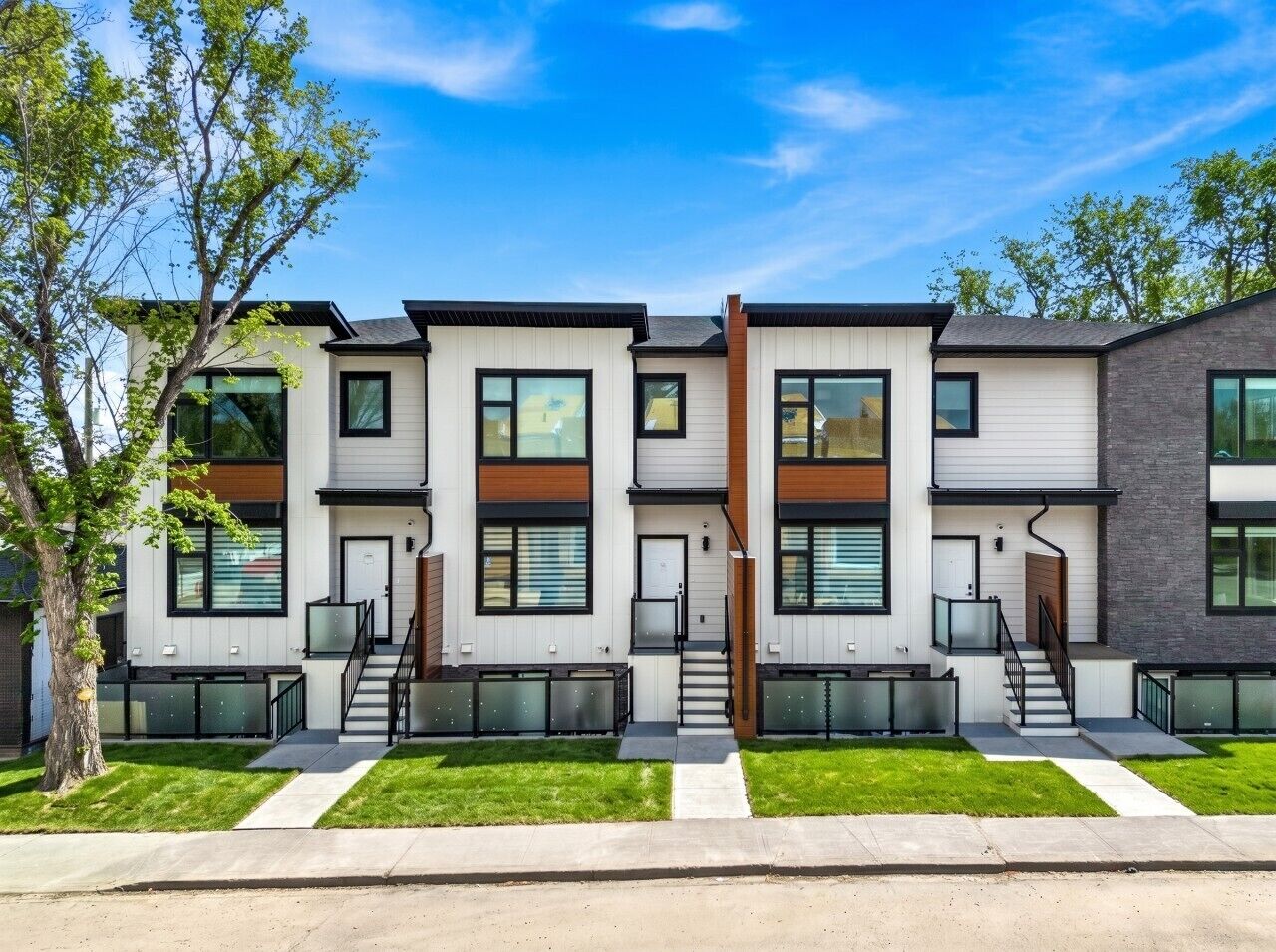 A modern multi-story residential building with a symmetrical facade, large windows, and a central staircase.