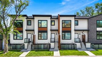 A modern multi-story residential building with a symmetrical facade, large windows, and a central staircase.