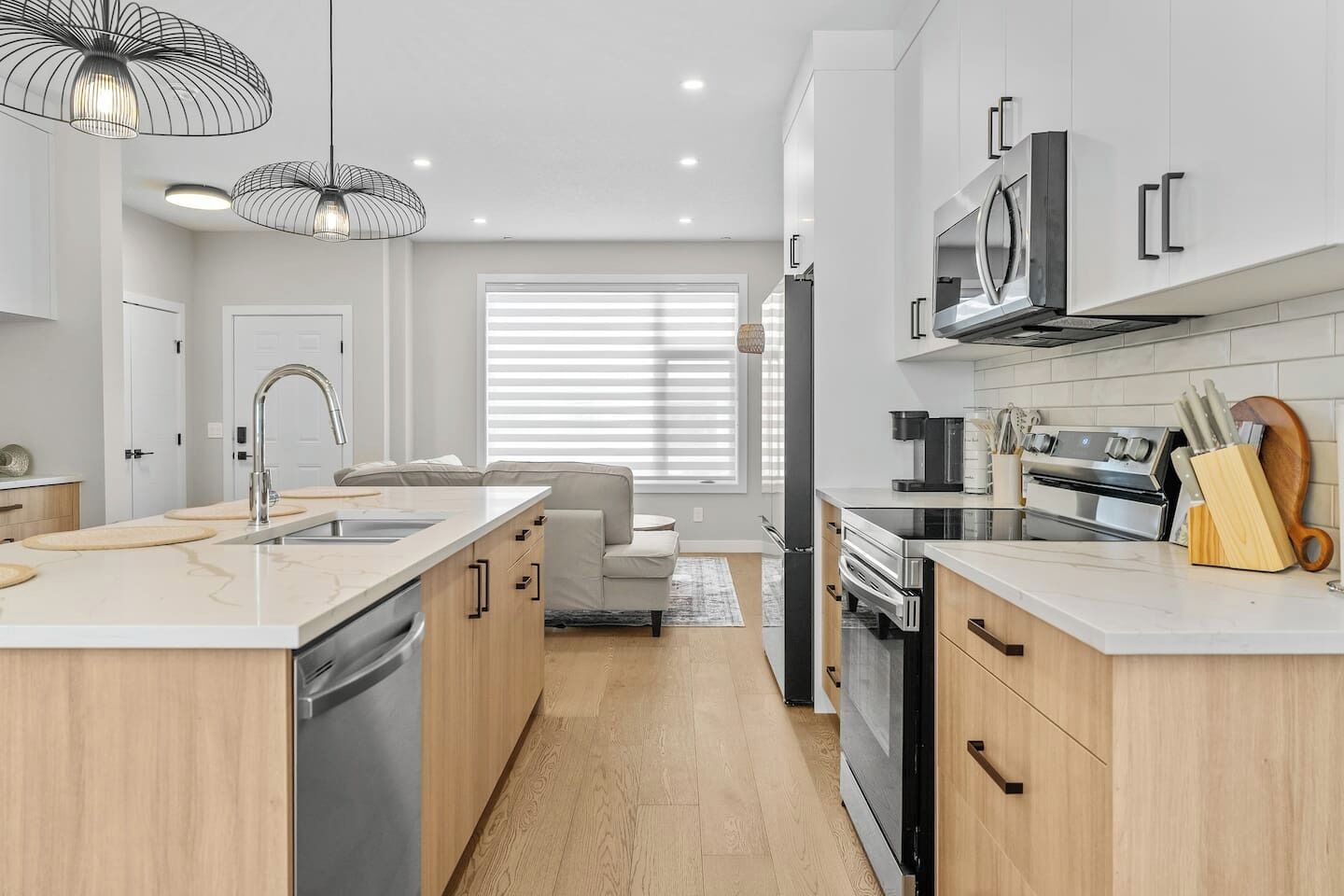 A modern kitchen with a central island, built-in appliances, and pendant lighting.