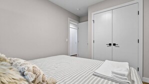 Ein Schlafzimmer mit einem Bett, einem großen Kleiderschrank und einer Tür zu einem weiteren Raum.
