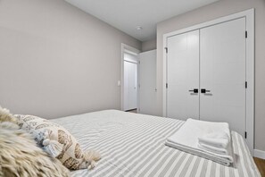Ein Schlafzimmer mit einem Bett, einem großen Kleiderschrank und einer Tür zu einem weiteren Raum.