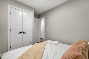A bedroom with a bed, a white door, and a hallway leading to another room. - King Bed | Min to UofC | NEW (Calgary)