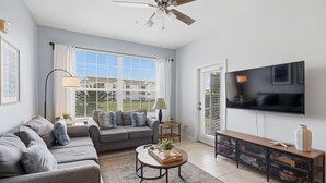 A living room with a sofa, coffee table, TV, and storage units. - NEW! Sunshine Stay at Windsor Palms - Near Disney (Kissimmee)