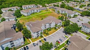 An aerial view of a residential complex with multiple apartment buildings, green spaces, and parking areas. - NEW! Sunshine Stay at Windsor Palms - Near Disney (Kissimmee)