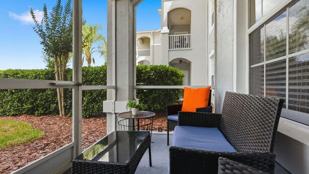 A balcony with wicker furniture, a small table, and a potted plant. - NEW! Sunshine Stay at Windsor Palms - Near Disney (Kissimmee)