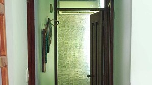 Ein schmaler Flur mit einer Holztür rechts und einer Wand mit Muster im Hintergrund.