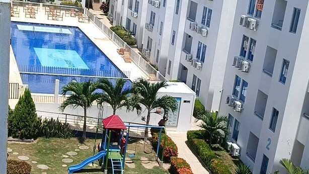Ein Wohngebäude mit Schwimmbad, Kinderspielplatz und gepflegtem Garten.