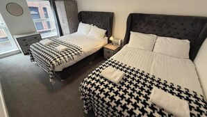 Une chambre d’hôtel avec deux lits, une fenêtre, un bureau et une chaise.