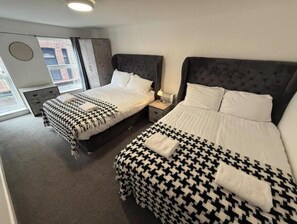 Ein Hotelzimmer mit zwei Betten, einem Fenster, einem Schreibtisch und einem Stuhl.