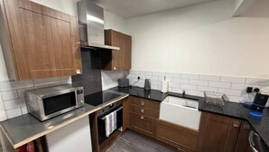 Une cuisine de taille réduite, dotée de meubles en bois, d’un four à micro-ondes, d’un évier et d’une cuisinière.