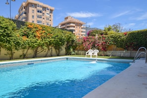 A swimming pool with a geometric tile border, surrounded by lush greenery and flowering plants. - Ref: 230. Fully renovated seafront studio with pool (Fuengirola)