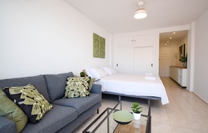 A modern living room with a sofa, a bed, a glass coffee table, and a small plant. - Ref: 230. Fully renovated seafront studio with pool (Fuengirola)
