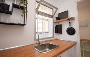 A kitchen with a wooden countertop, stainless steel sink, and a window with metal bars. - Ref: 230. Fully renovated seafront studio with pool (Fuengirola)