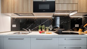 Una cocina moderna con microondas negro, pileta de acero inoxidable y salpicadero de mármol.