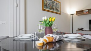Una mesa con platos, vasos, pan y un florero con flores.