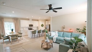 Uma sala de estar moderna com um sofá, uma mesa de centro e um espaço de jantar com cadeiras e uma mesa.