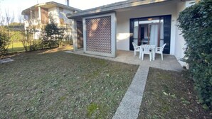 Una propiedad residencial con un porche cubierto, un pequeño jardín y una puerta que da a un garaje.