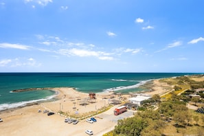 A coastal area with a beach, parking lot, and buildings.