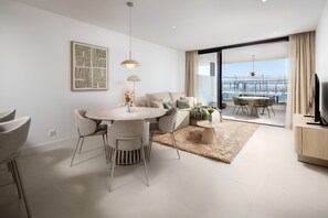 A modern living room with a dining area, a TV, and a large window with a view of a bridge. - AS EXT Higueron Lomas 4-2b (Fuengirola)