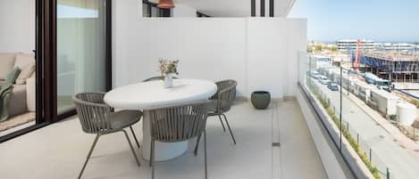Un balcon moderne avec une table et des chaises pour les repas, un canapé et une vue sur un chantier de construction.