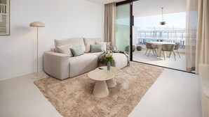 A modern living room with a sofa, a coffee table, and a view of a balcony with a dining area. - AS EXT Higueron Lomas 4-2b (Fuengirola)