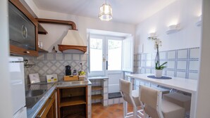 Uma cozinha com forno embutido, pia, janela e um balcão com cadeiras.