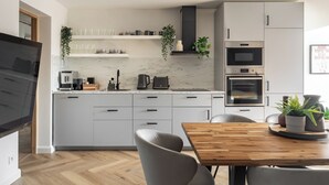A modern kitchen with white cabinets, a wooden dining table, and a built-in oven. - Casablanca - Near the Beach Sopot (Sopot)