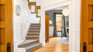 Una escalera que sube a un segundo piso, una puerta de madera y un pasillo con alfombra.