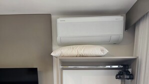 A room with a mounted TV, an air conditioning unit, a shelf with a folded towel, and a hanging coat rack. - Flat 109 Norte Novo e Completo 204 (Brasília)