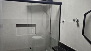A modern bathroom with a glass-enclosed shower, a white toilet, and a sink with a black countertop. - Flat 109 Norte Novo e Completo 204 (Brasília)