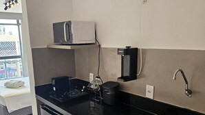 A kitchen with a black countertop, a built-in dishwasher, a coffee machine, and a microwave. - Flat 109 Norte Novo e Completo 204 (Brasília)