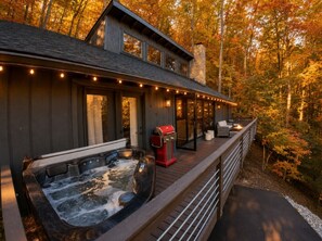 Ein Whirlpool auf einer Terrasse mit einem Steinkamin, umgeben von Herbstlaub.