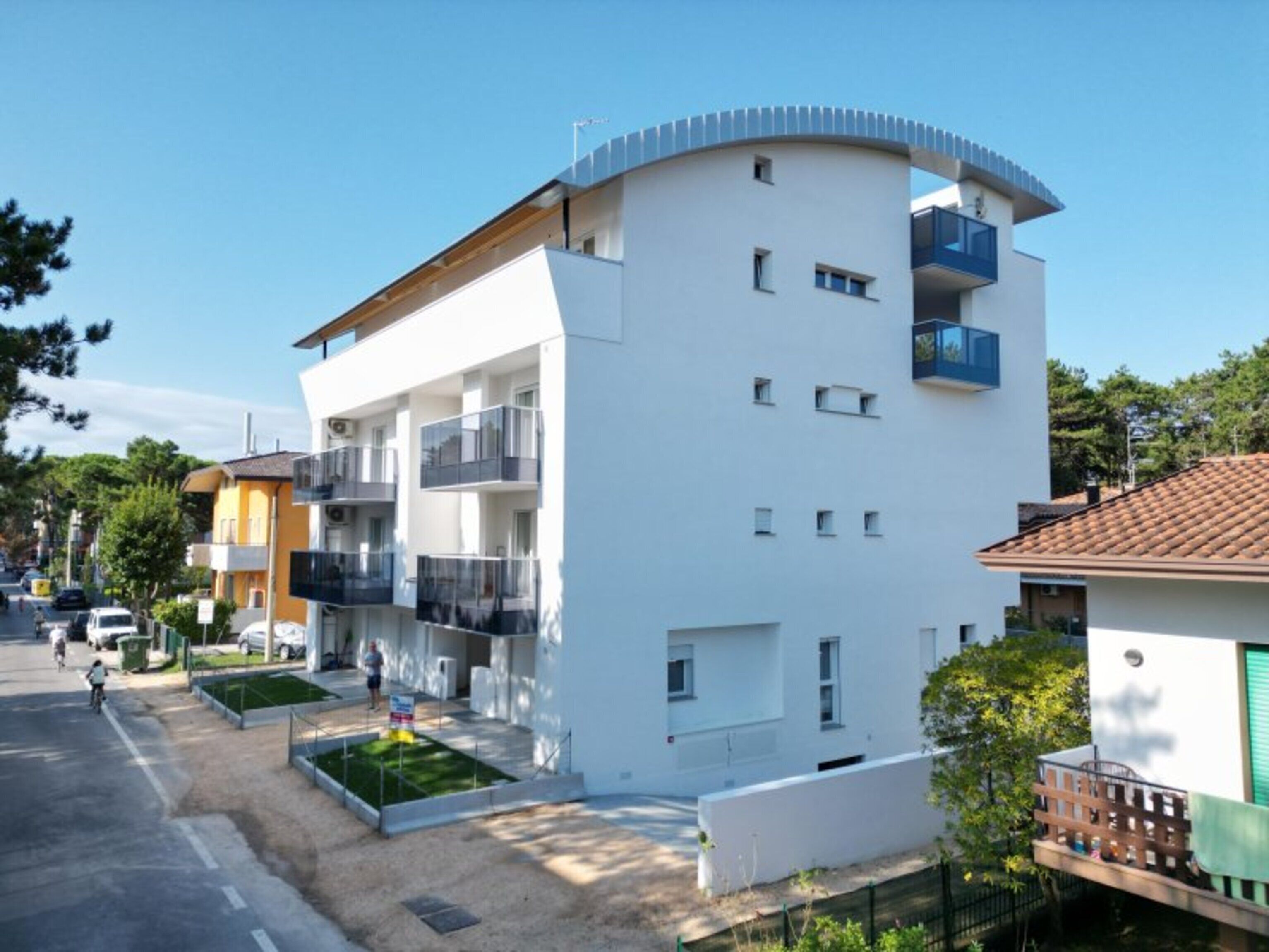 A modern multi-story building with balconies, a flat roof, and a clean, urban environment.