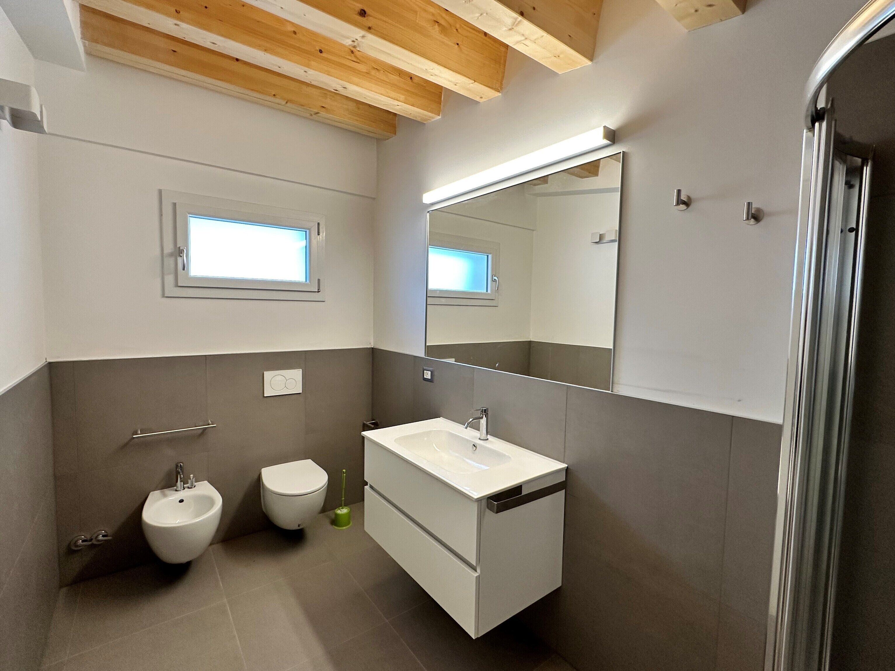 A modern bathroom with a bidet, a sink, and a mirror.