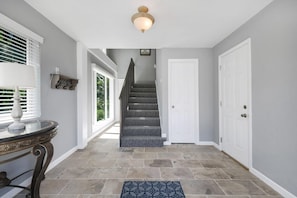 Ein Flur mit Treppe, einer weißen Tür und einem Tisch mit Lampe.